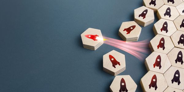 Wooden hexagons with rocket icons, one launching forward symbolizing innovation.