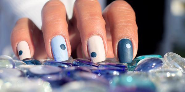 Blue and white nail art with dots on glass pebbles.