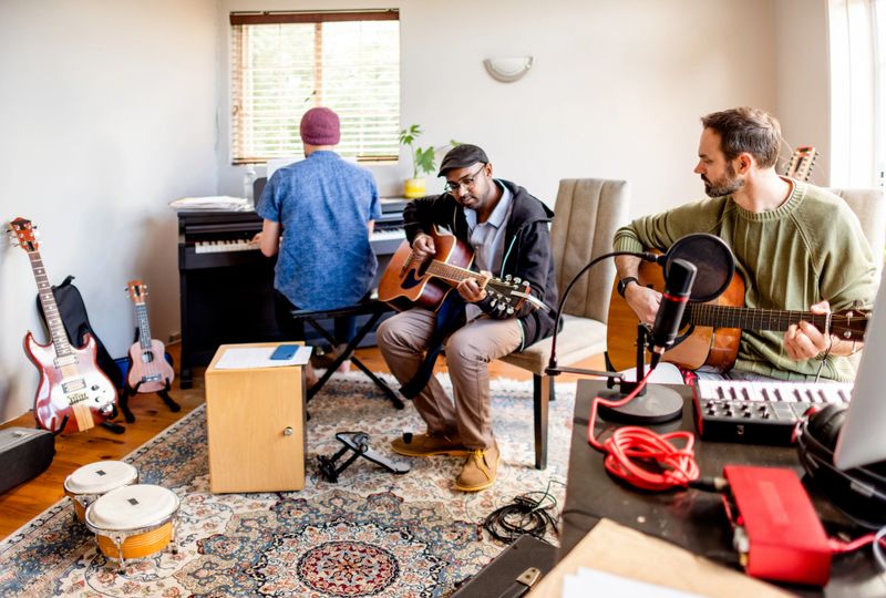 Diverse group of young musicians playing different instruments during a rehearsal together in a home studio