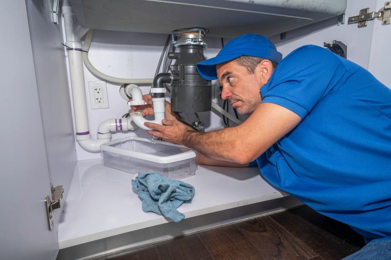 Plumber working on pipes under a kitchen sink