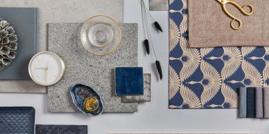 A flat lay of elegant blue, beige, and gold decor and fabric samples.