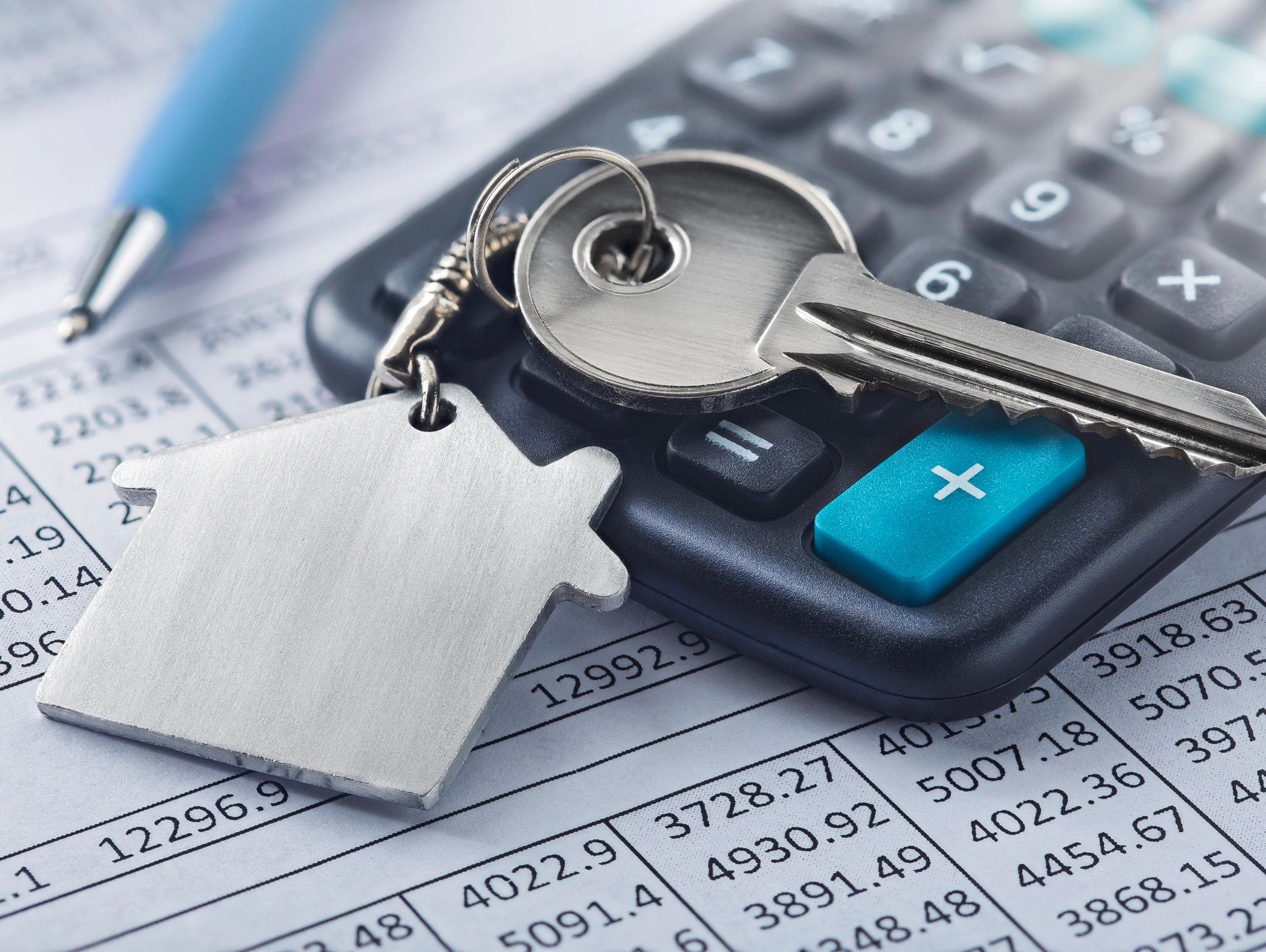 House keys resting on a calculator and mortgage paperwork