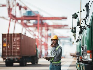 Construction worker using a walkie-talkie at a shipping port.