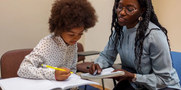 A woman tutors a young girl working on her homework.