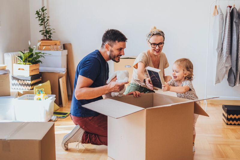Happy family with one child unpacking boxes in new home on moving day