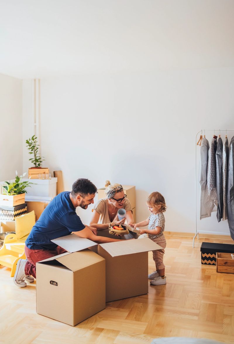 Happy family with one child unpacking boxes in new home on moving day