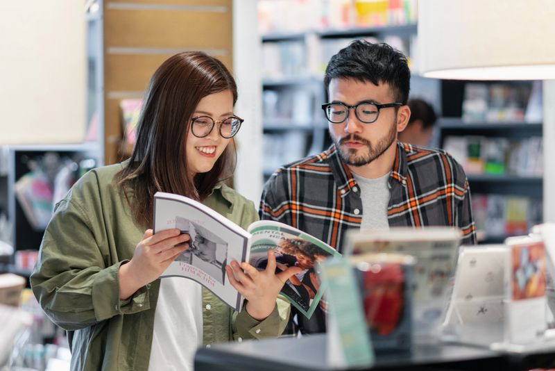 Young couple looking at magazines in the bookstore together. Okayama, Japan