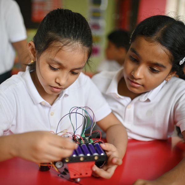 Two girls working on an electronics project together.