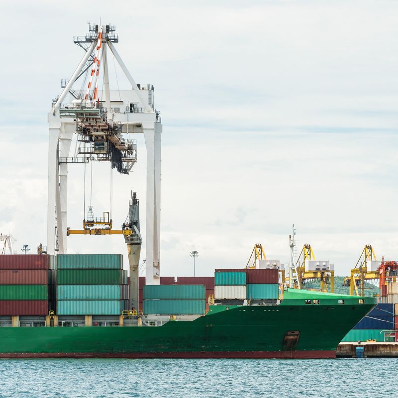 Container Cargo freight ship with working crane bridge in shipyard at dusk for Logistic Import Export background