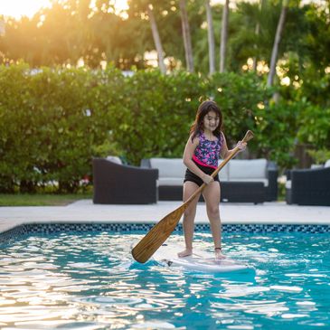 girl swimming in pool on paddleboard