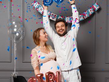 Couple celebrating gender reveal with confetti.