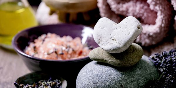 Spa essentials with stones, lavender, salt, and a towel.