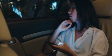 Woman sitting in car at night looking out the window.