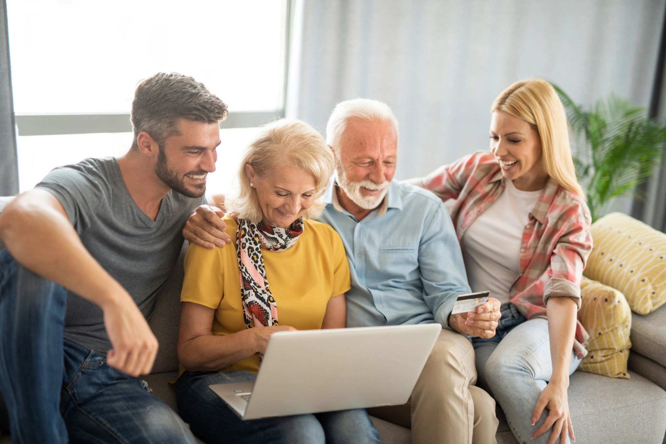 Family enjoying online shopping together on a laptop with a credit card.