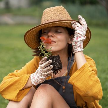 Woman enjoying the scent of a flower while gardening.