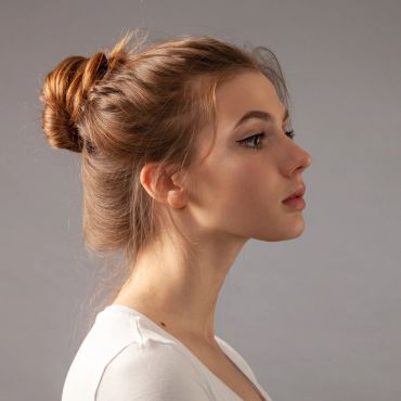Profile of a young woman with hair in a bun.