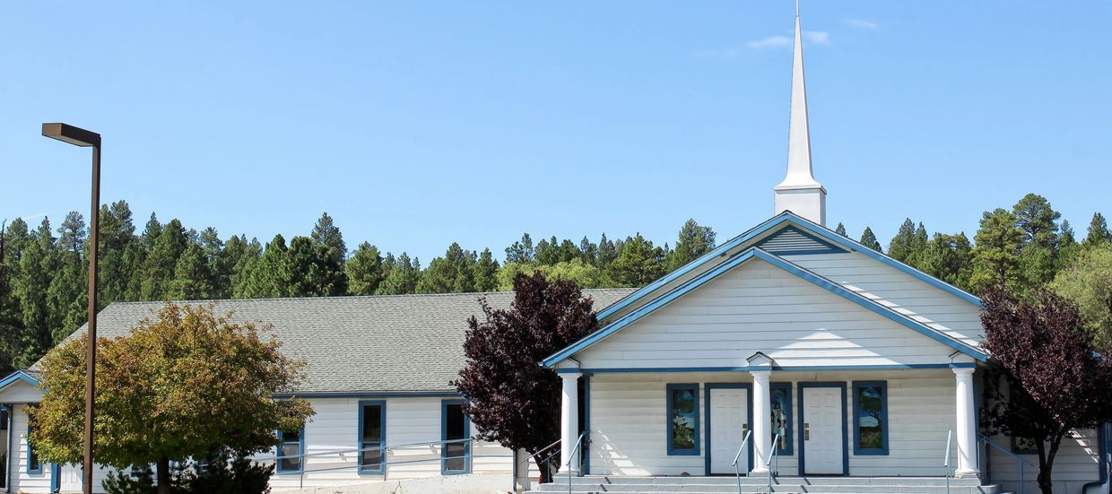 A small church building with a parking lot and clear blue sky.