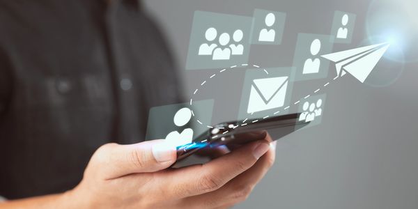 Person holding smartphone with digital icons of messages and contacts.