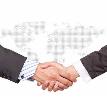 Two businesspeople shaking hands with a dotted world map in the background.