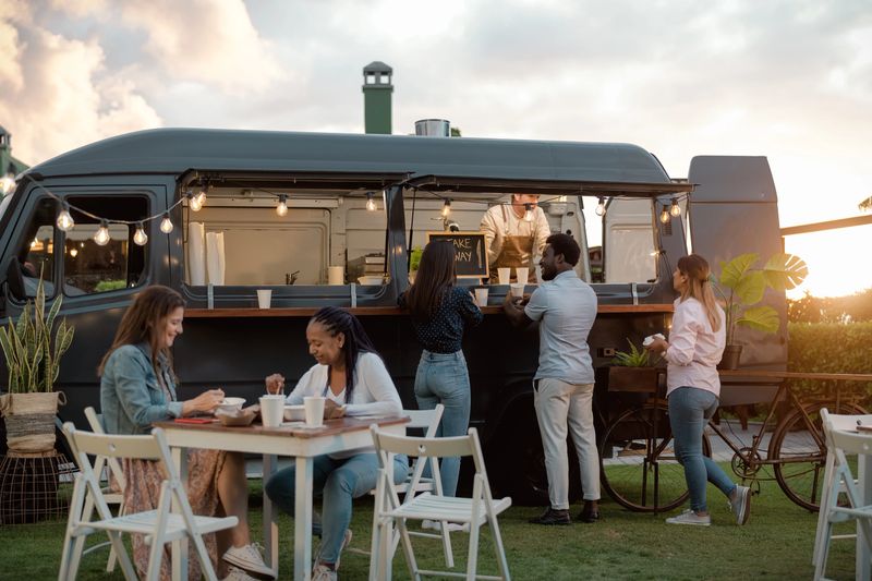 Happy multiracial people having fun eating in a street food truck market