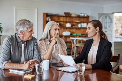 A professional woman discussing documents with an elderly couple at home.
