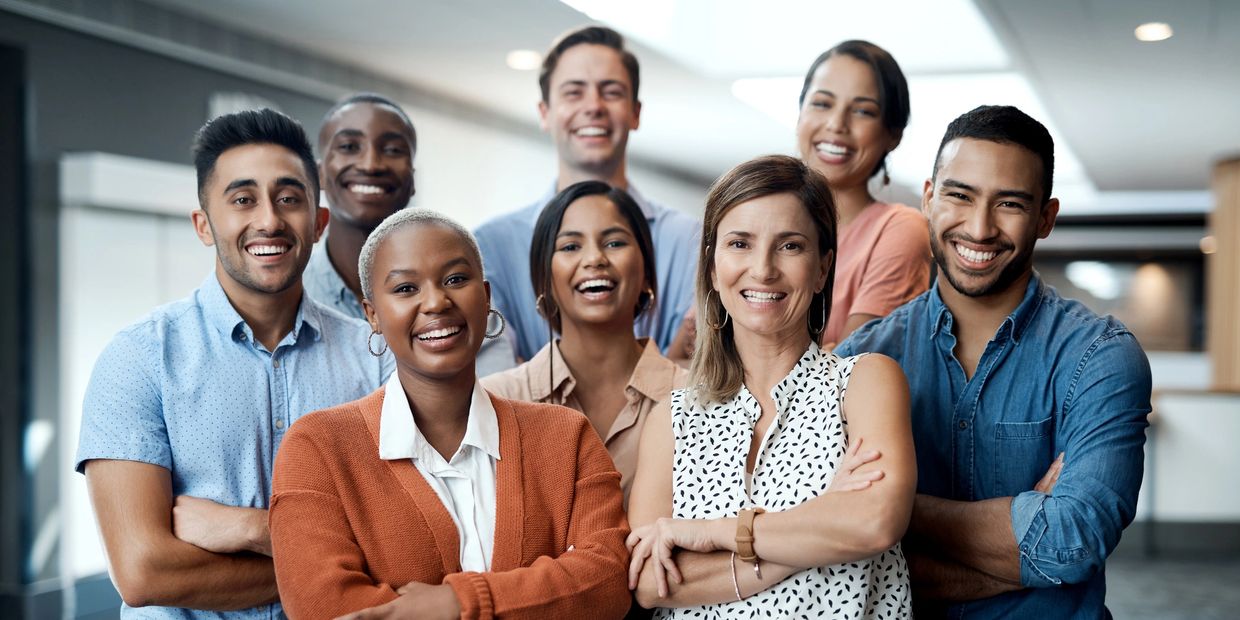 A diverse group of smiling professionals standing with arms crossed.