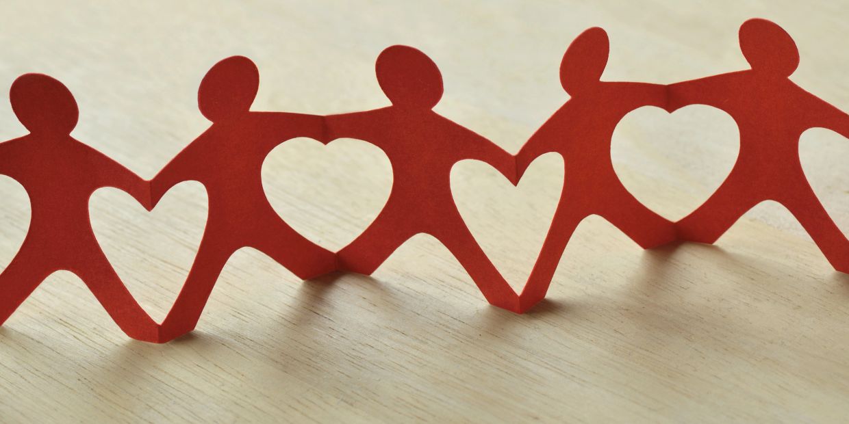 Red paper chain of figures with heart shapes in the center, symbolizing unity and love.