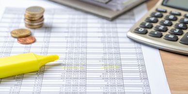Financial data spreadsheet, coins, and highlighter for tax and accounting at andeanconsultants.net