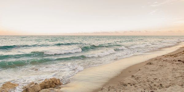 Calm ocean waves gently washing onto a sandy beach at sunset.