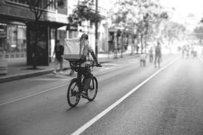 Delivery person riding a bicycle on city street.