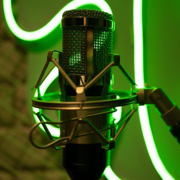 Close-up of a studio microphone with green neon lights in the background.