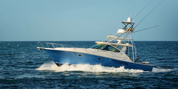 Blue and white fishing boat cruising on calm ocean waters.