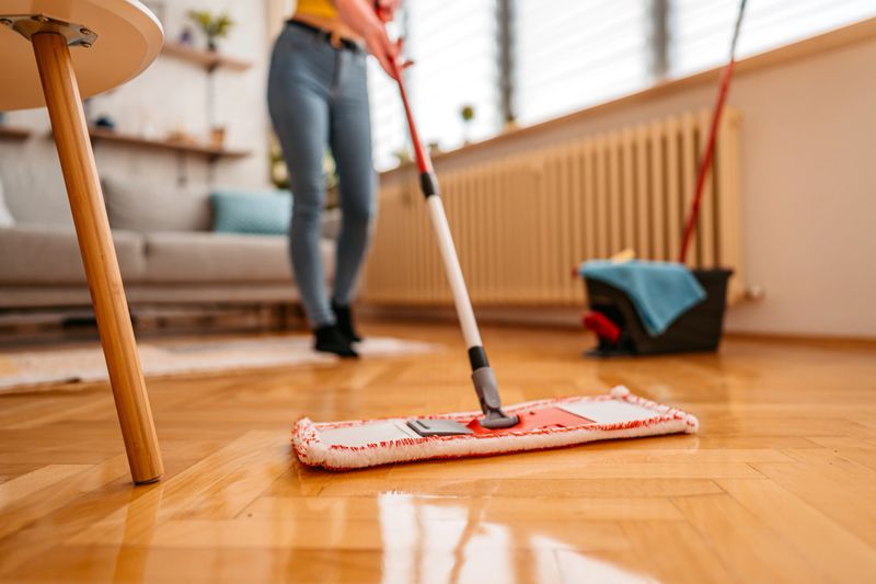 Cleaning parquet floor with wet mop, close up.