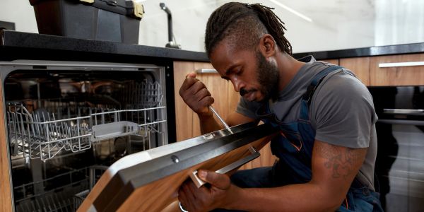 Technician repairing a dishwasher.