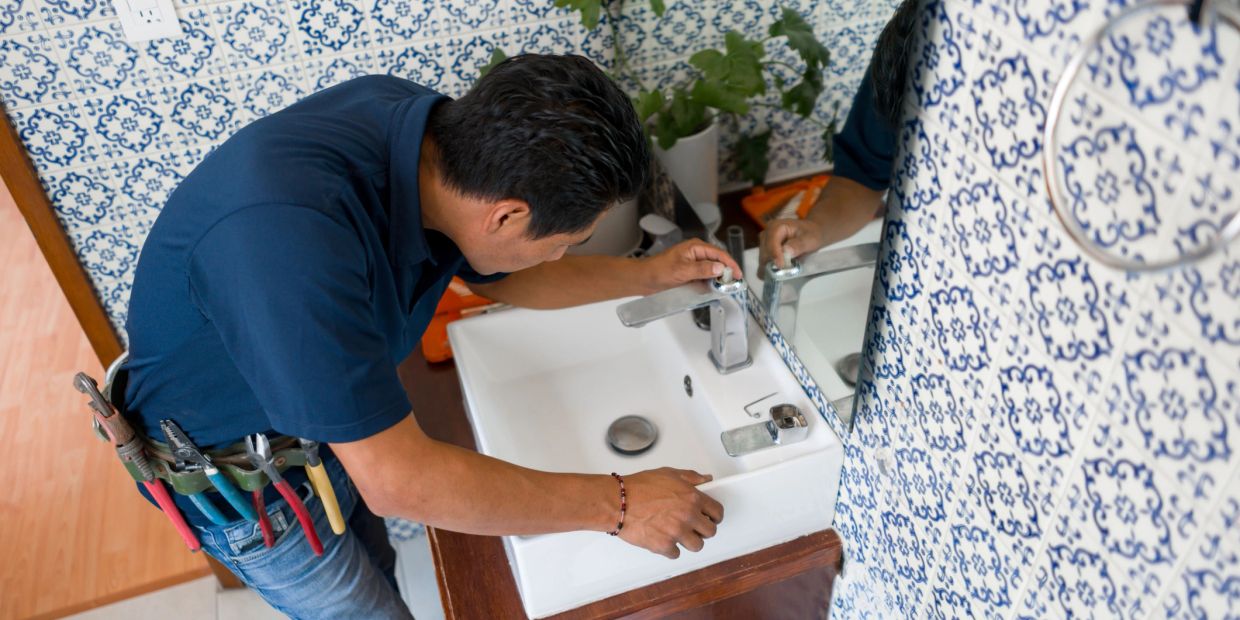 Plumber fixing a bathroom sink faucet.