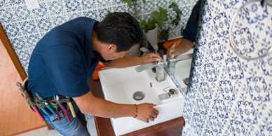 Plumber fixing a bathroom sink faucet.