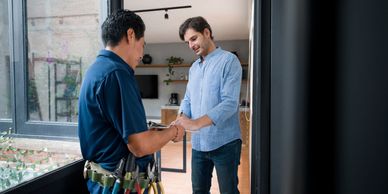 Technician and homeowner discussing and signing a service document at the door.
