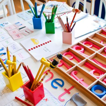 Colorful pencils and letter learning materials on a table.