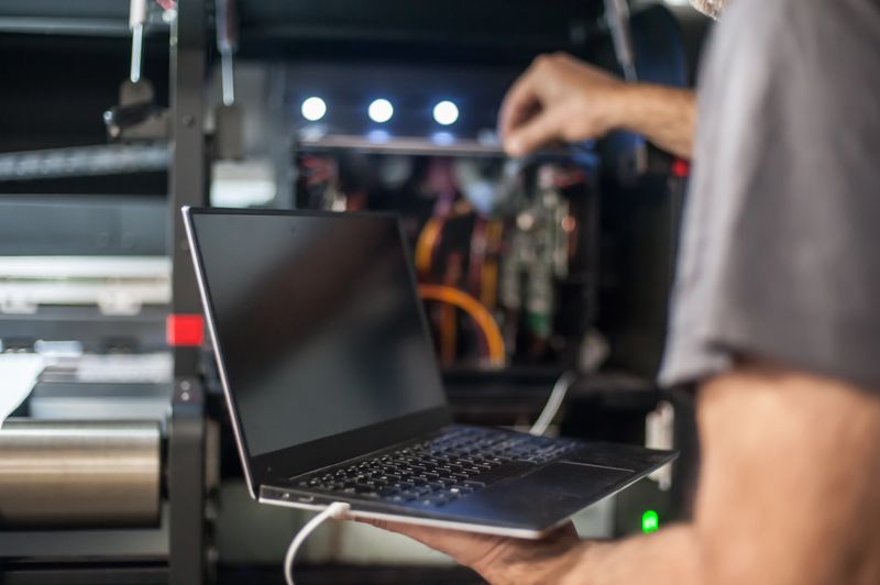 Field service maintenance engineer technician electrician inspect and control machine hardware and software system with laptop computer. Electric installation