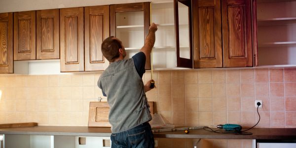 Man installing wooden kitchen cabinets.