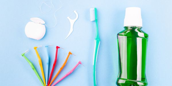 Assorted dental hygiene tools including floss, interdental brushes, toothbrush, and mouthwash.