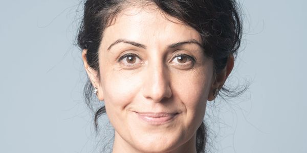 Close-up portrait of a smiling woman with dark hair against a light background.