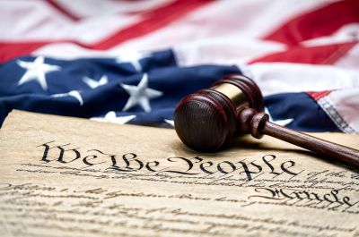 Gavel on the U.S. Constitution with American flag.