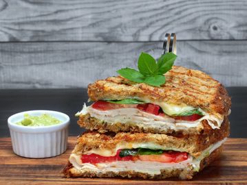 Grilled sandwich with melted cheese, fresh vegetables.