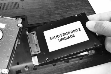 Hand installing a solid state drive for a laptop upgrade.