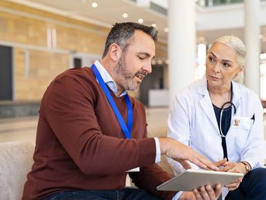 Man discussing medical information with a female doctor using a tablet.