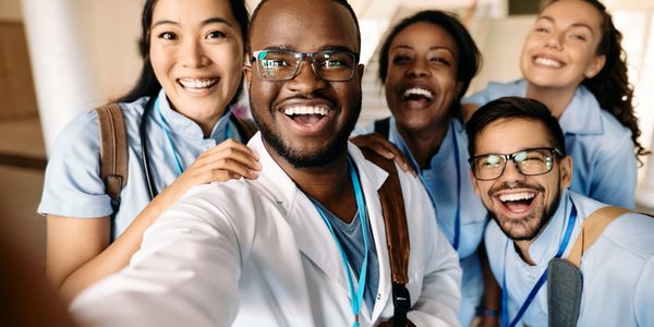 A diverse group of smiling healthcare professionals taking a selfie together.