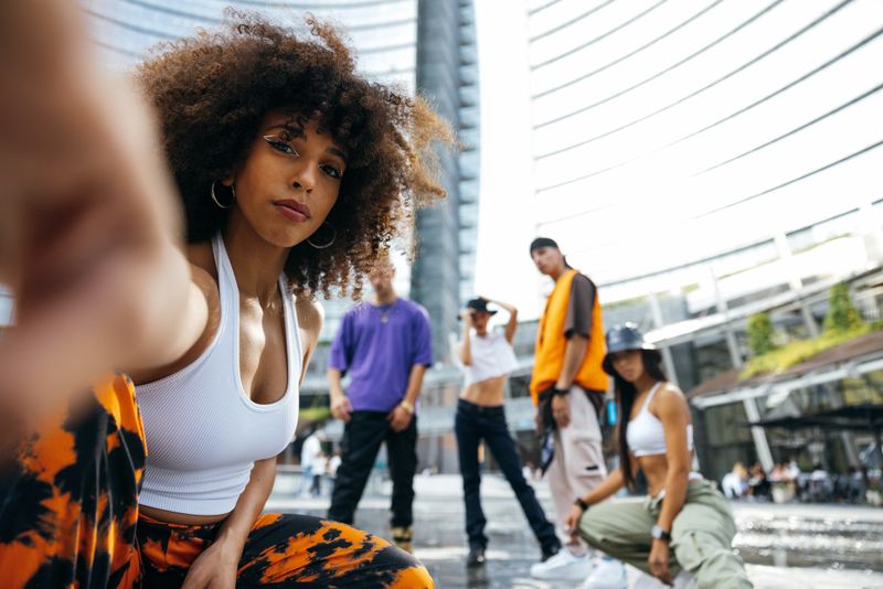 Young multiethnic performers dancing with Rap music in the city streets.