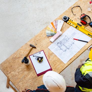 Construction planning with blueprints and tools on the wooden table.