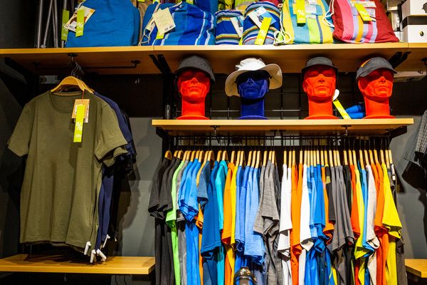 Colorful T-shirts and hats displayed in a retail store with discount tags.